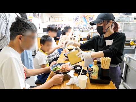 A udon restaurant that has long queues in the parking lot of a factory