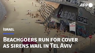 Beachgoers run to take shelter as sirens wail in Tel Aviv | AFP