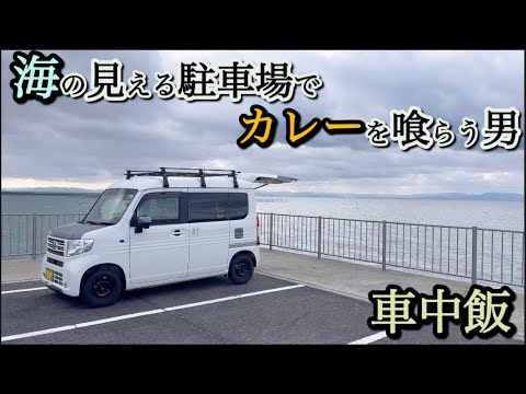 [Meal in a car] A man who eats curry in a parking lot with a view of the sea