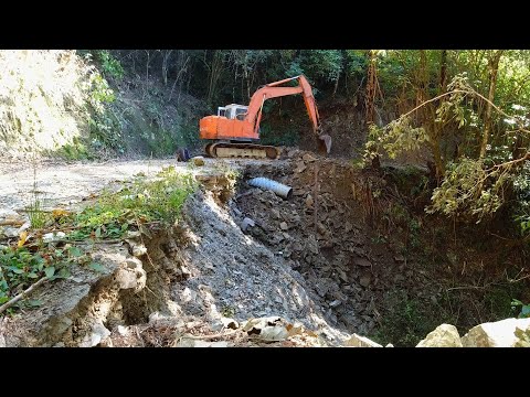 Abandoned Excavator rebuilding washed out road and installing new culvert pipe.