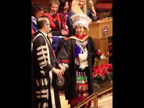 This Chinese student in traditional ethnic attire takes the stage to receive their diploma