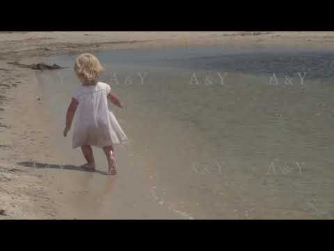 Beautiful little girl runs along the seashore. Little girl in a white dress on the coast. Slow