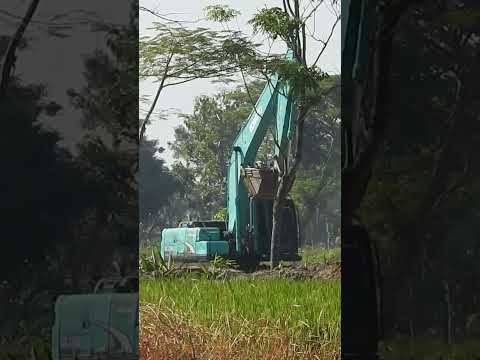 Kobelco SK200 crawling to other space on a toll construction road