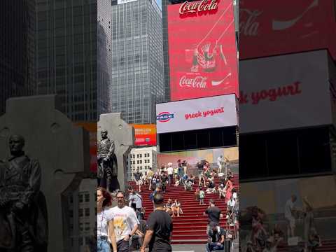 Vibrant Times Square with Father Duffy’s statue and neon signs shining bright during the day! #nyc