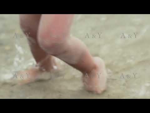 A small child splashing in the water on the beach. Slow motion