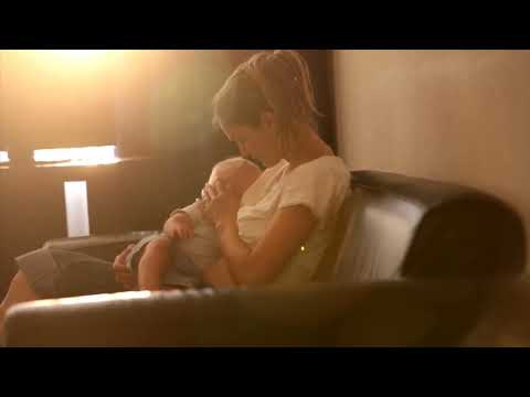 Young mother, breastfeeding on sunset on quiet evening her little baby boy in sunny living room