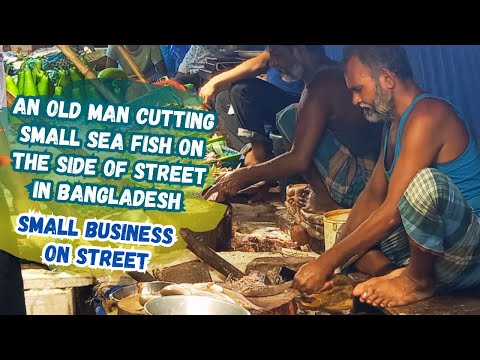 An old man cutting small sea fish for the customers on the side of Street in Bangladesh