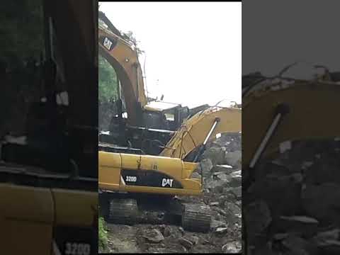 Duo Cat excavators Working on a hill under the rain